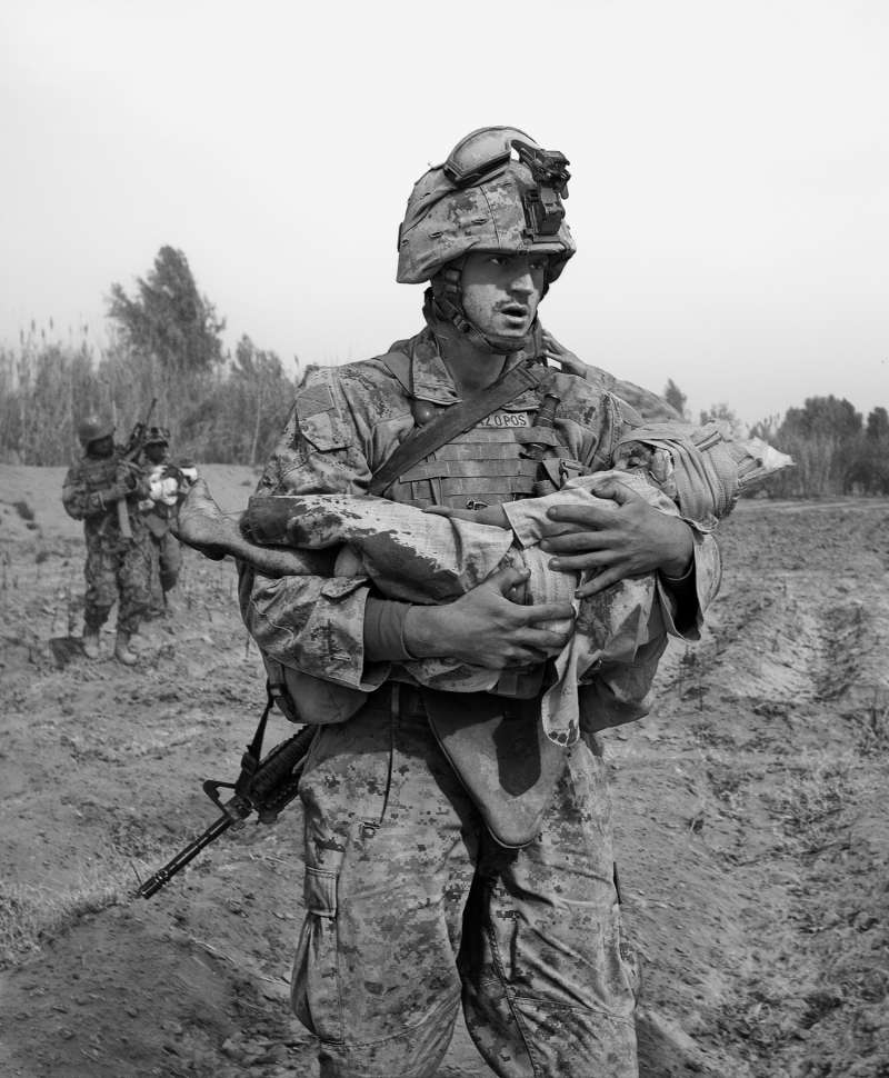 A Marine carries an Afghan child, one of two wounded by coalition aircraft during an air support mission.
