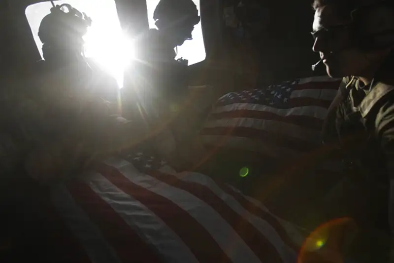 Kandahar Province, Afghanistan: Air Force pararescuemen ride in the back of a medevac helicopter with the bodies of two U.S. soldiers killed in a roadside bomb attack in Kandahar Province, October 10, 2010. Photographer Guttenfelder describes the scene: When the pararescue guys were covering the bodies, they only had two flags with them. The wind was shipping through the open window...and the wind caught it and it blew out the window and they lost it. So they only had one flag. (But) one of the pilots had a flag that he kept behind the plate of his flak jacket, one that he'd kept with him for every deployment he'd ever done: Iraq, Afghanistan. He flew over Washington DC with it, his children had kissed it. He took it out and passed it to the back of the helicopter and that was one of the flags they used to cover one of the guys. The family of the soldier who died, who was covered by the donated flag, has reached out to me to ask for a contact for the pilot. They are hoping to give the flag back to him.