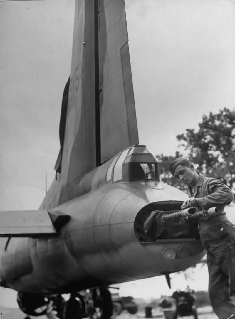 A B-17 Flying Fortress tail gunner cleans machine guns he recently used to down a German plane in a bombing raid over Europe in 1942.