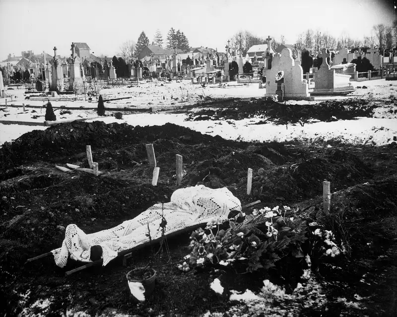 A lace curtain shrouds the body of an American soldier awaiting burial in the Bastogne cemetery.