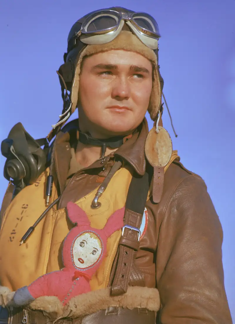 A B-17 bomber crewman carries a child's bunny doll tucked into the waistband of his flight suit and a Mae West life preserver in England, 1942.