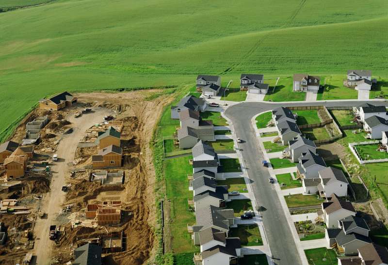 Housing development under construction on farmland, aerial view.