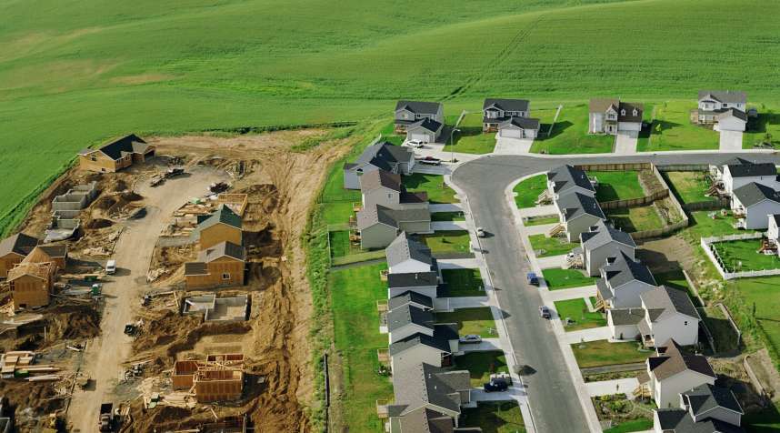 Housing development under construction on farmland, aerial view.