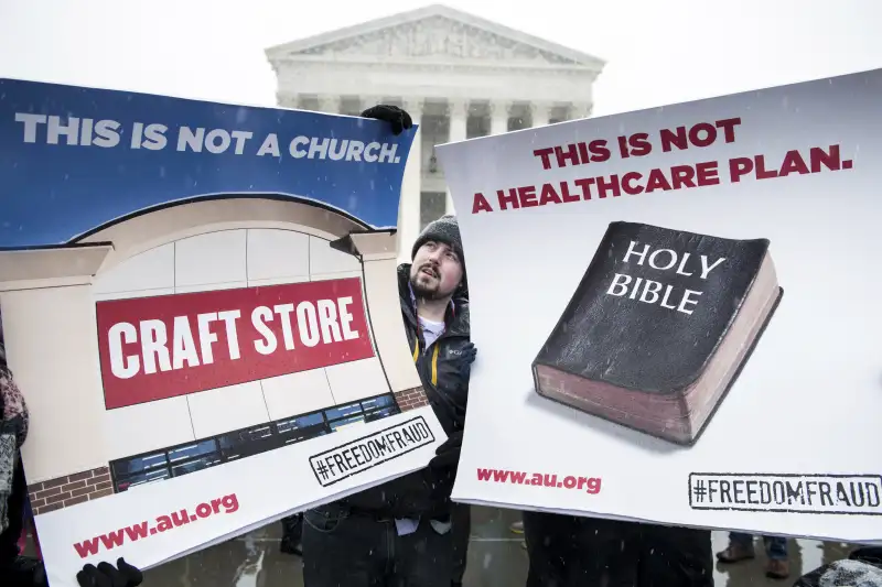 Activists holding signs about Hobby Lobby case standing outside the Supreme Court