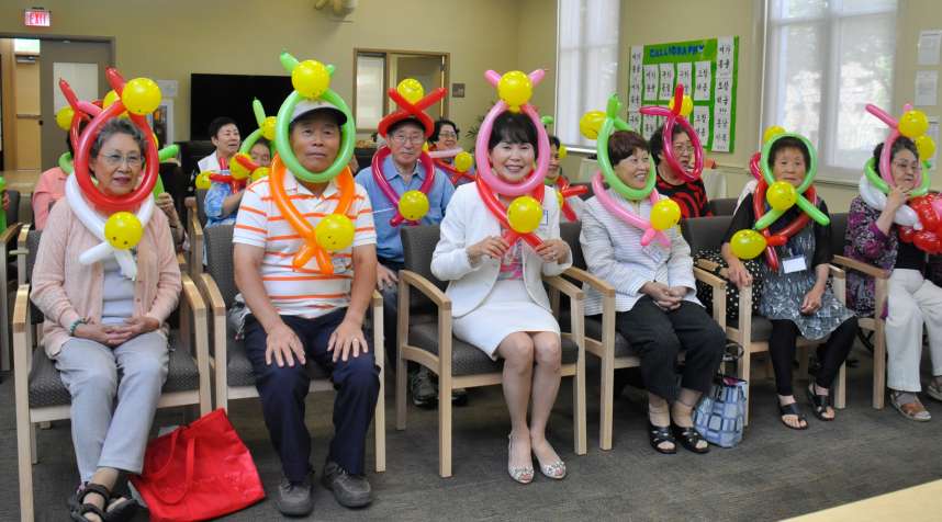 Im Ja Choi (center, in white suit), founder of Penn Asian Senior Services, celebrates with clients at the opening of her agency's first adult day  care facility, the Jubilee Center in Philadelphia.
