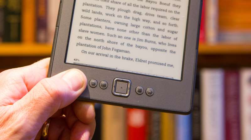 Amazon Kindle in front of a bookshelf