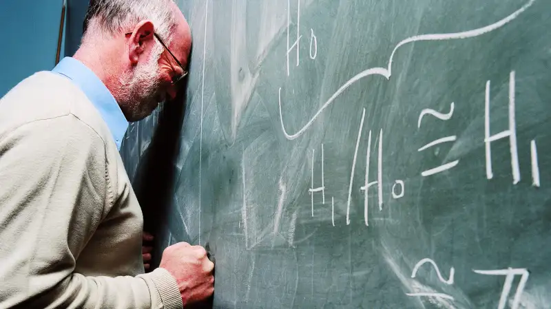 Man slamming his head into chalkboard of theorems in frustration