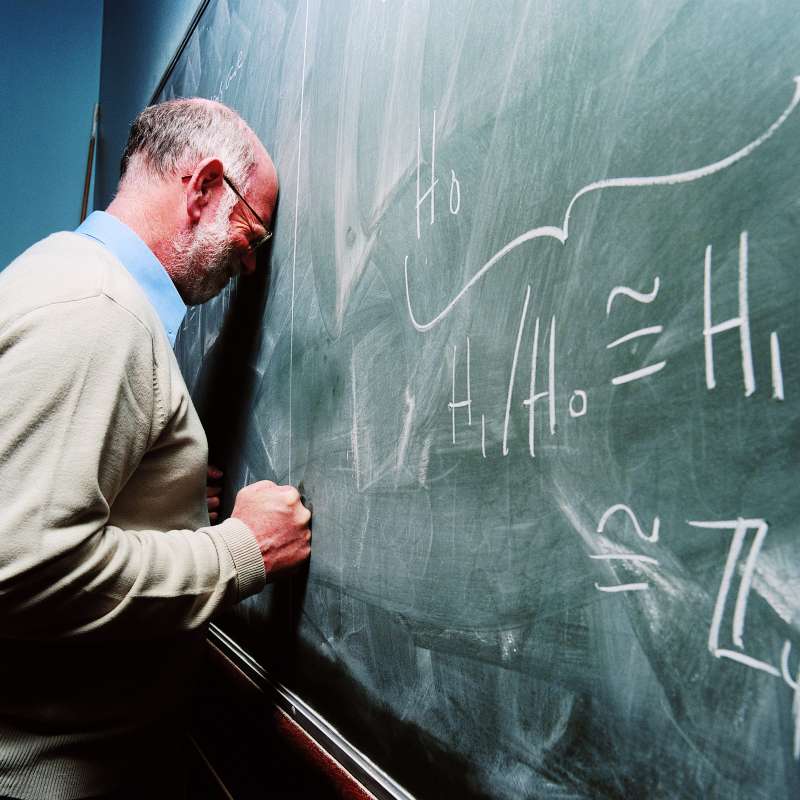 Man slamming his head into chalkboard of theorems in frustration