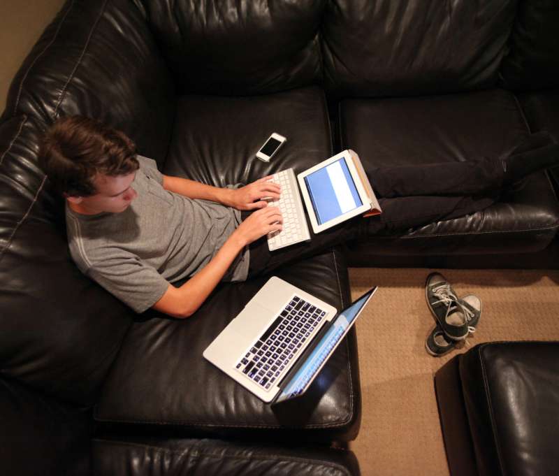 Teen using laptop, tablet and smartphone