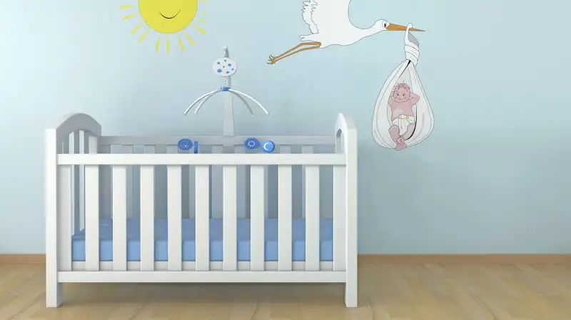 Empty crib with stork and baby on wall