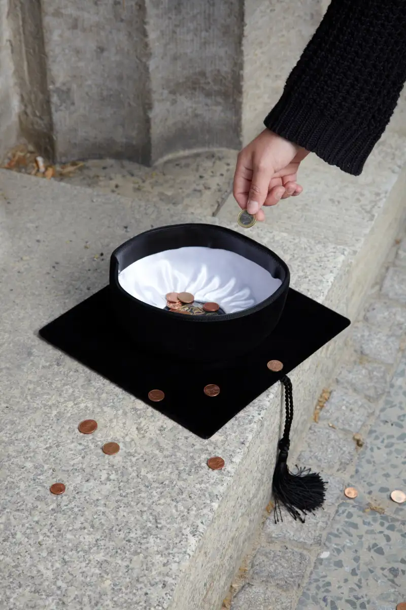 Graduation cap on sidewalk with change in it