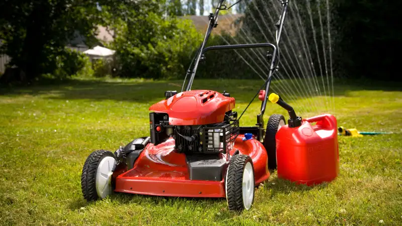 Red lawn mower and sprinkler on lawn