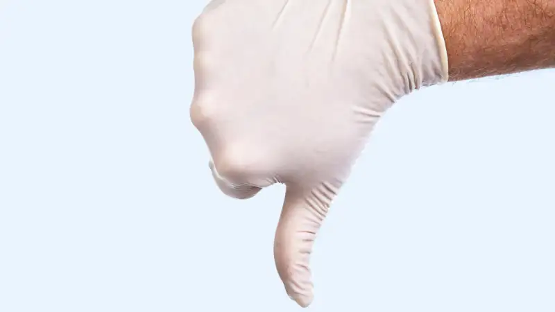 Hand in medical glove with thumbs down