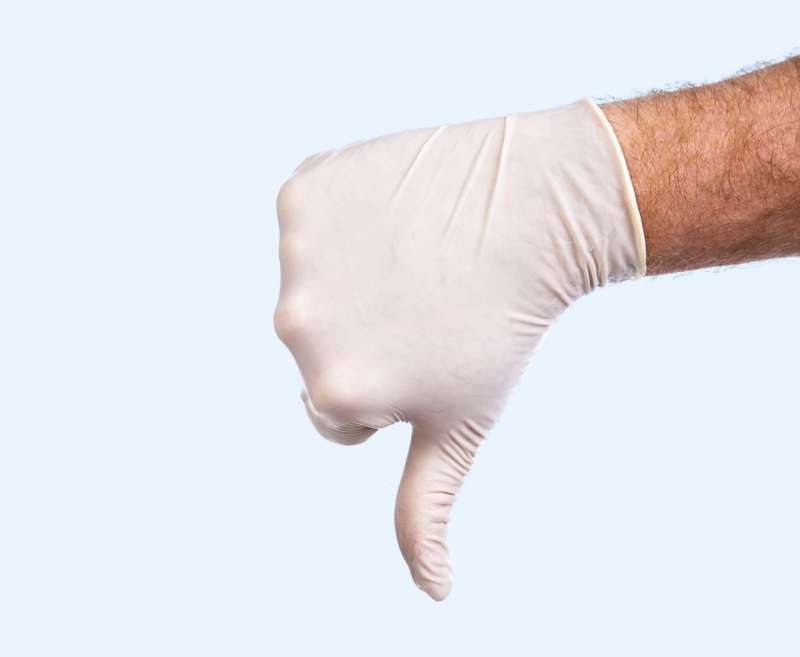 Hand in medical glove with thumbs down