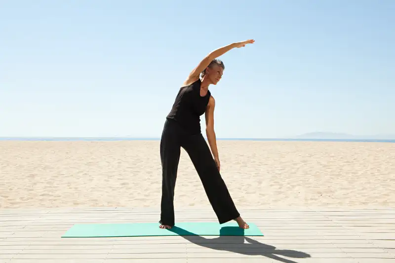 Senior doing yoga on beach