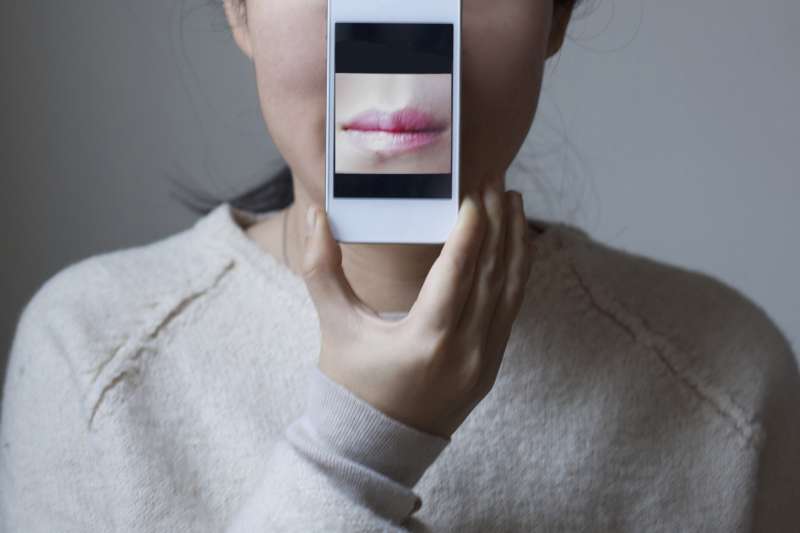 woman with iphone image of her mouth in front of her mouth