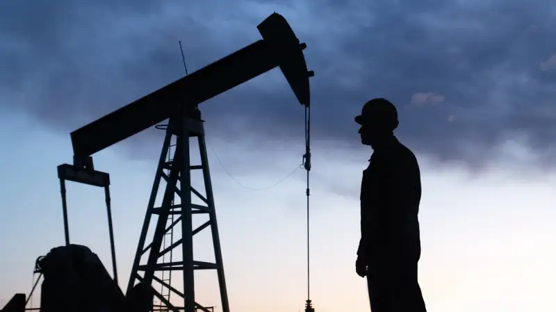 Man looking at oil rig in silhouette