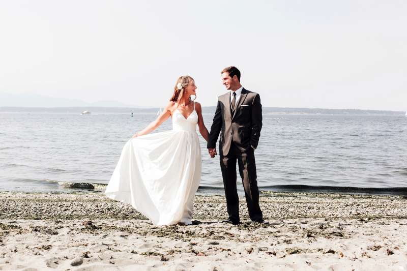 A bride and groom on a beach at the water's edge in Kirkland, Washington. Kirkland is a top place for both men and women to find a spouse.