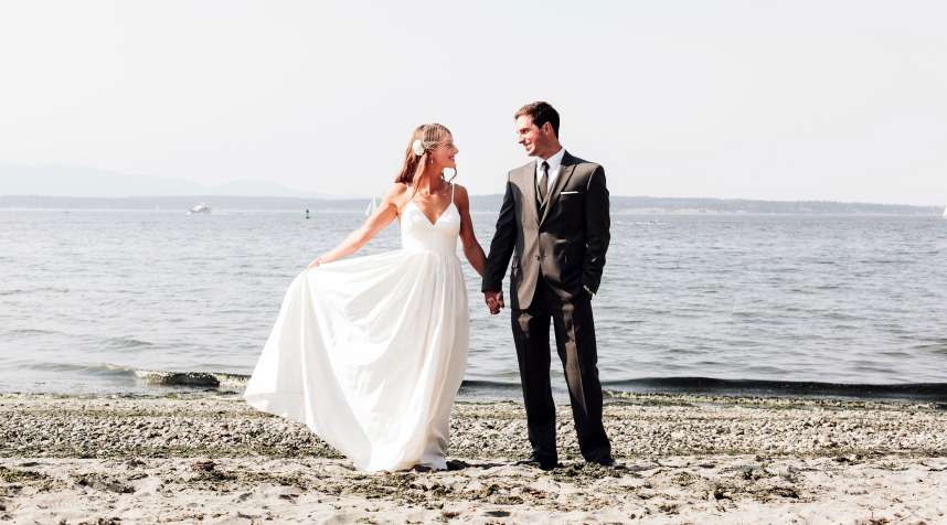 A bride and groom on a beach at the water's edge in Kirkland, Washington. Kirkland is a top place for both men and women to find a spouse.