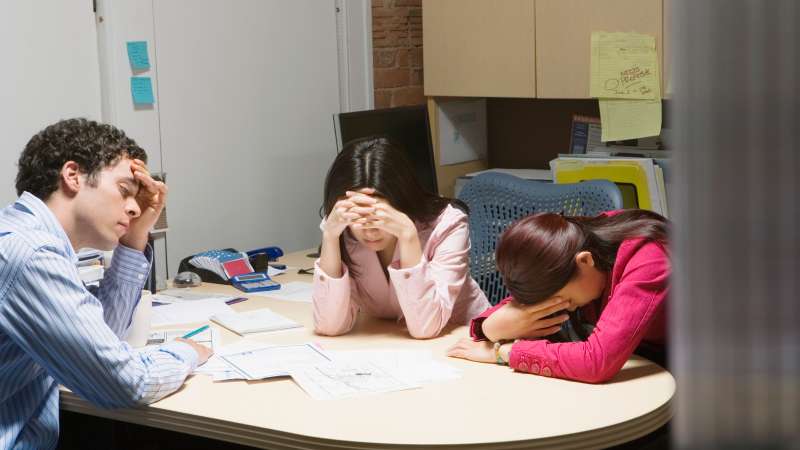 Sad millennials leaning on desks