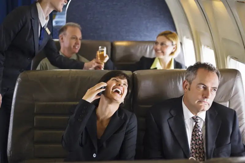 woman using cell phone on plane and annoying fellow passengers