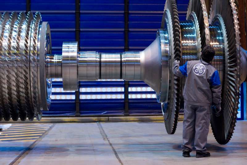 A General Electric Co. employee examines a component for a gas turbine at the company's factory.