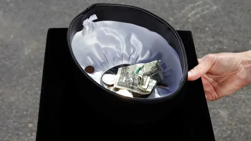 Hand holding out mortarboard begging for money