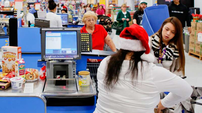 Employees wear Santa hats as customers check out at a Wal-Mart Stores Inc. location ahead of Black Friday in Los Angeles, California, U.S., on Tuesday, Nov. 26, 2013.