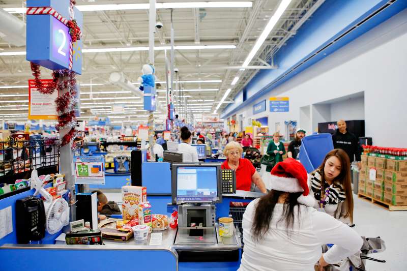 Employees wear Santa hats as customers check out at a Wal-Mart Stores Inc. location ahead of Black Friday in Los Angeles, California, U.S., on Tuesday, Nov. 26, 2013.