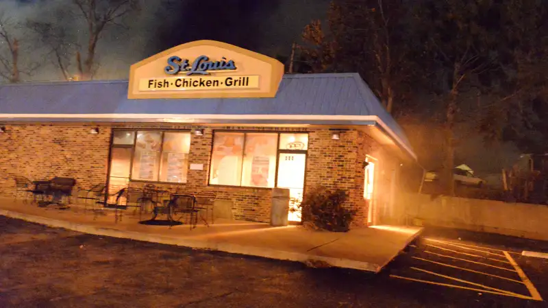 Flames illuminate the St. Louis Fish & Chicken Grill next door to where fire crews worked to douse a burning furniture store.