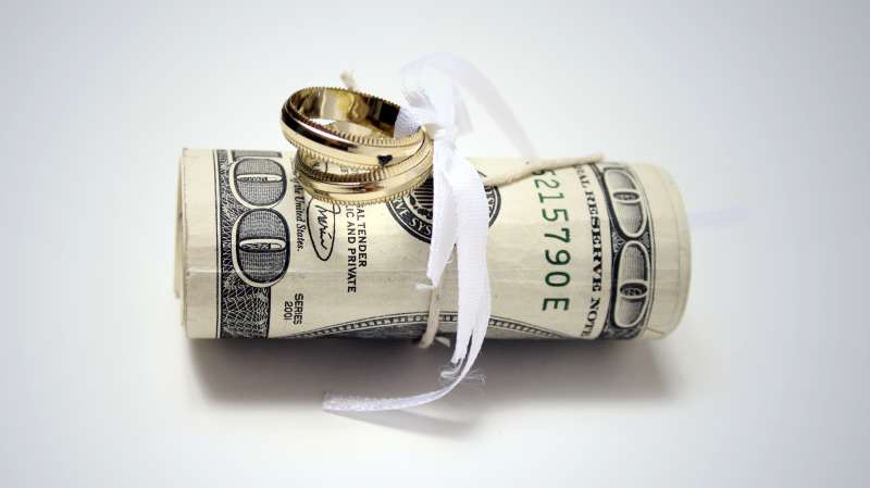 wedding rings tied to roll of $100 bills