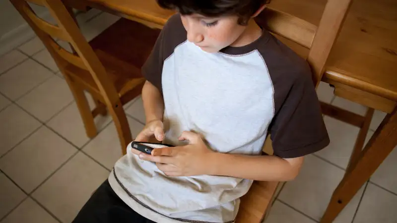 boy on smartphone in kitchen