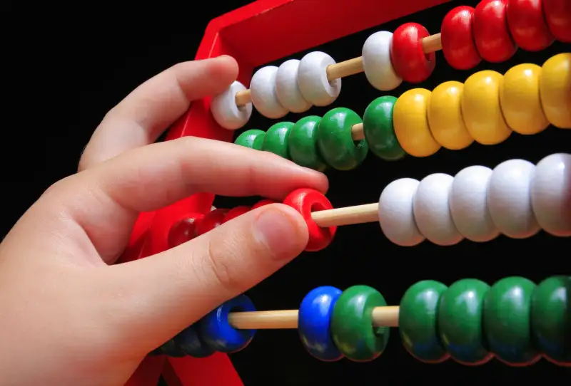 child's hand moving an abacus