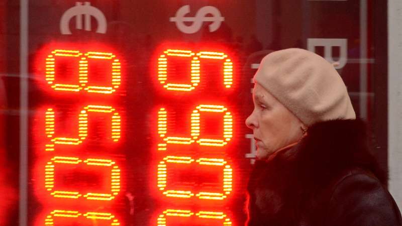 A woman walks past a board listing foreign currency rates against the Russian ruble outside an exchange office in central Moscow on December 16, 2014. The Russian ruble set a new all-time record low on Tuesday after bouncing back briefly despite an emergency move by Russia's central bank to raise interest rates to 17 percent.