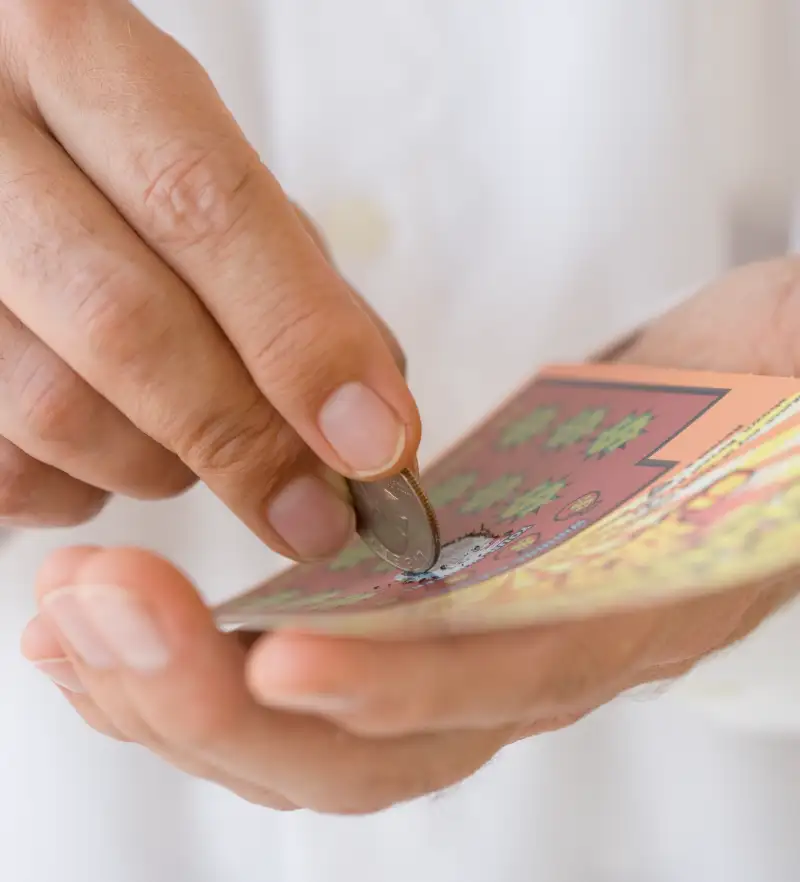 Man scratching lottery card with coin