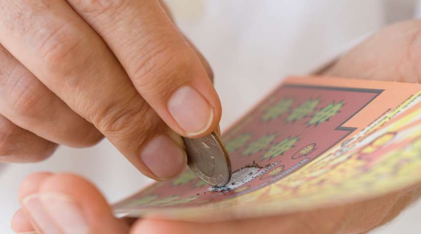 Man scratching lottery card with coin