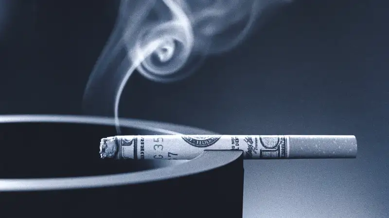 smoking cigarette wrapped in money on ashtray