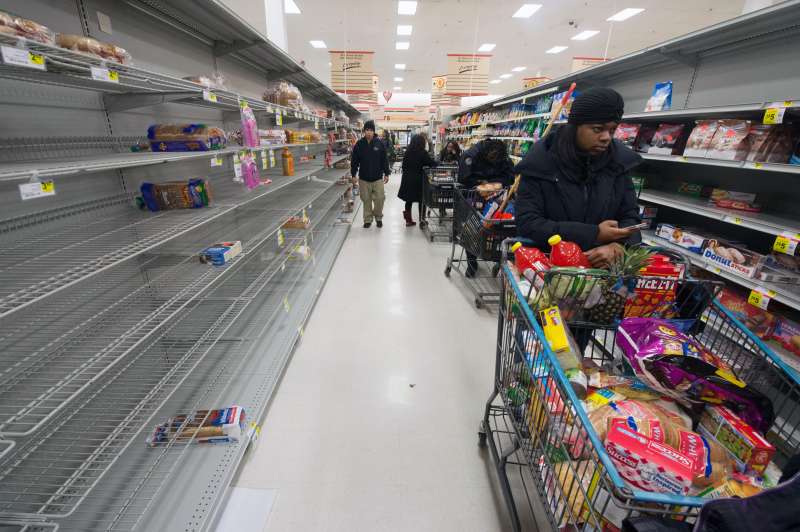 A long line of shoppers wait beside mostly-empty shelves in the bread aisle of a grocery store, as people stocked up on items ahead of an approaching snowstorm, in Alexandria, Virginia, USA, 12 February 2014.