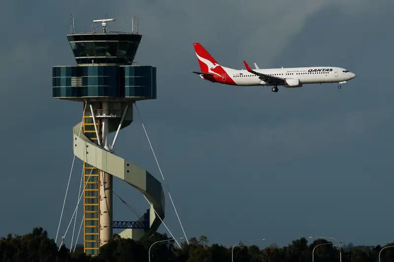 A Boeing Co. 737 aircraft operated by Qantas Airways Ltd. flies past the air traffic control tower as it lands at Sydney Airport in Sydney, Australia