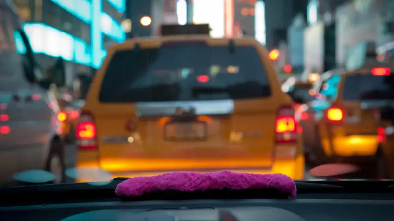 A pink mustache on the dashboard as Bouchaib El Hassani, 31, a Lyft driver, makes his way through midtown.