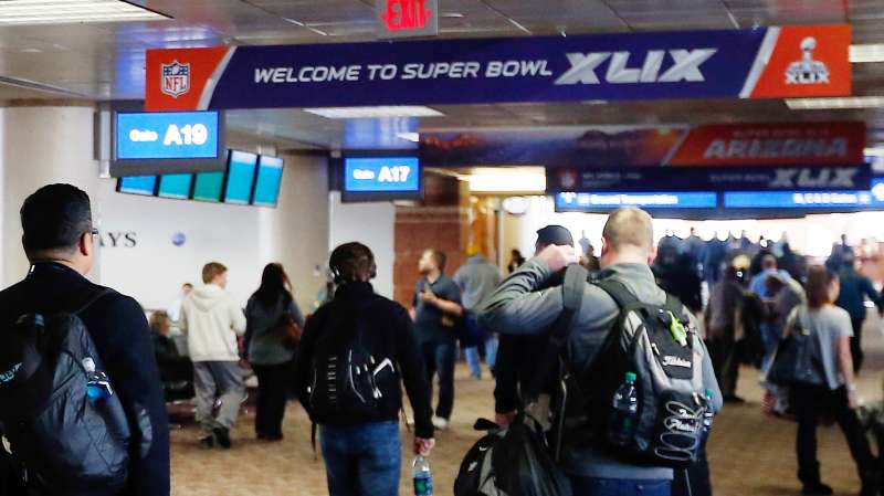 Travelers walk past Super Bowl XLIX logos at Phoenix Sky Harbor International Airport on January 19, 2015 in Phoenix, Arizona. The NFL Super Bowl XLIX will be held at the University of Phoenix Stadium on Febrauary 1, 2015.