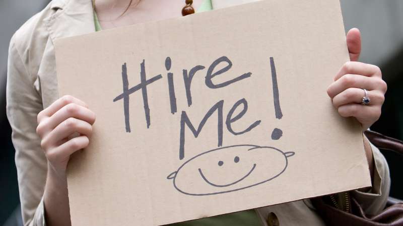 woman holding  Hire Me  sign