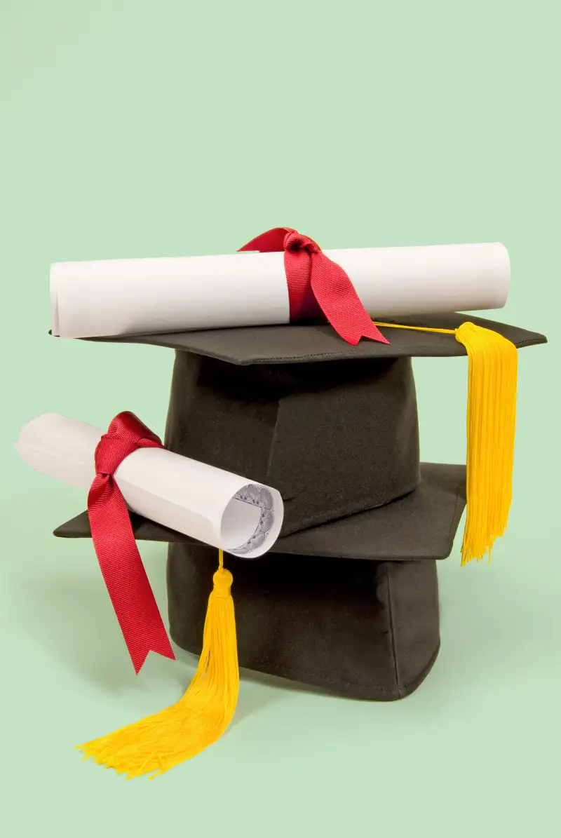 two diplomas two graduation caps stacked