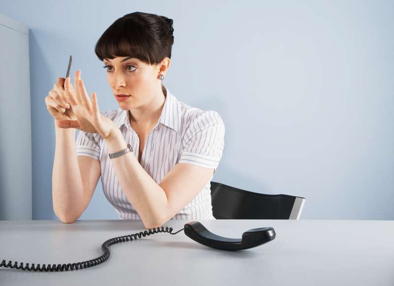 woman filing nails with phone off the hook in the office
