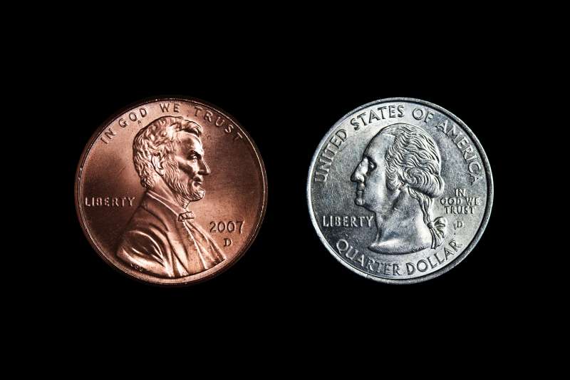 Lincoln on penny and Washington on Quarter facing one another on black background