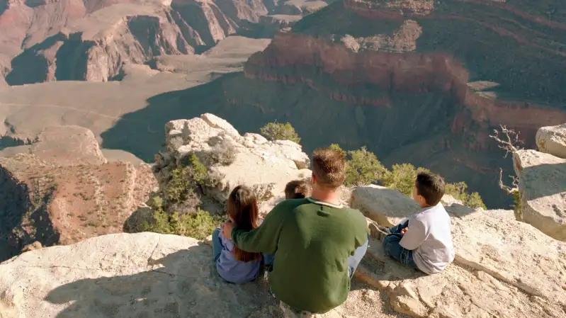 family sitting on the edge of the Grand Canyon