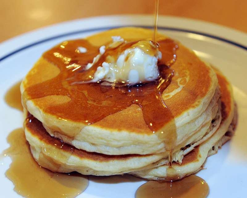 Maple syrup runs down the side of a short stack of three pancakes at the International House of Pancakes.