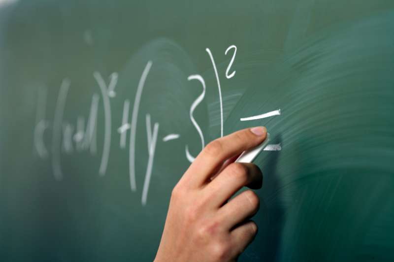 hand doing math equations on chalkboard