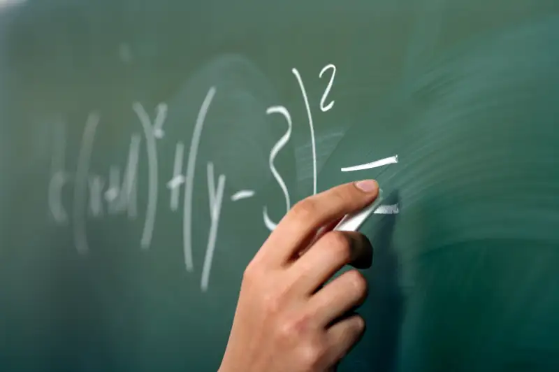 hand doing math equations on chalkboard