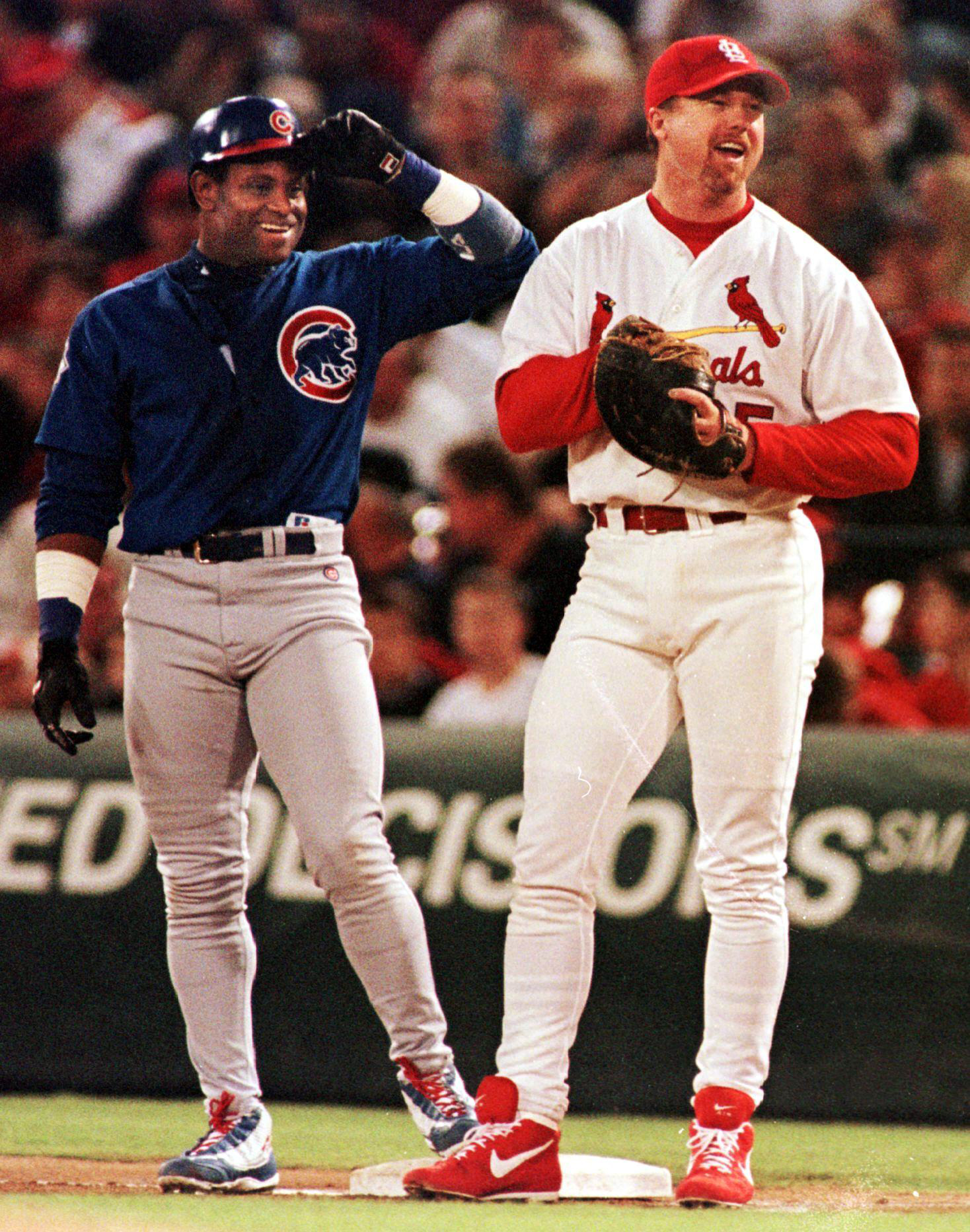 Chicago Cubs' Sammy Sosa (L), shares a laugh with St. Louis Cardinals' first baseman Mark McGwire (R), after receiving a walk in the third inning. McGwire stayed at 63 home runs and Sosa stayed at 62 as neither had a home run in the 3-2 Chicago victory.